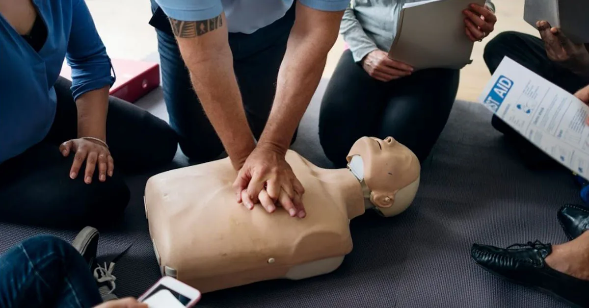 Students practicing chest compressions on a CPR manikin in a Red Safety class