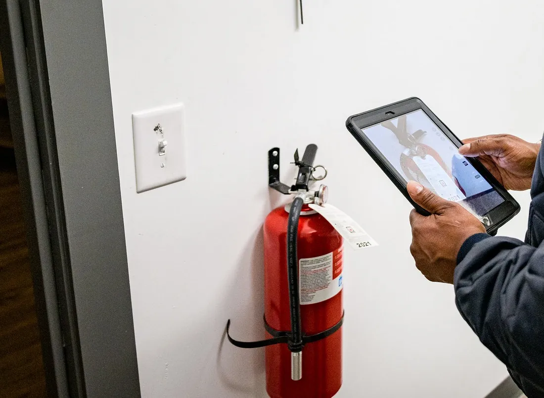 Inspector logging a fire extinguisher on a tablet during an inspection